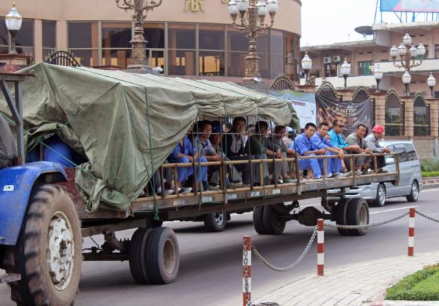 In this photo taken on May 20, 2015, Chinese workers travel on the back of a trailer pulled by a tractor on their way to work in Kinshasa, Democratic Republic of Congo. Congos government is bringing in outside experts including officials from the World Bank and the United Nations, to investigate the long-term impact of some $6.7 billion in contracts with Chinese companies that critics have said could exploit the central African nations mineral riches.(AP Photo/John Bompengo)