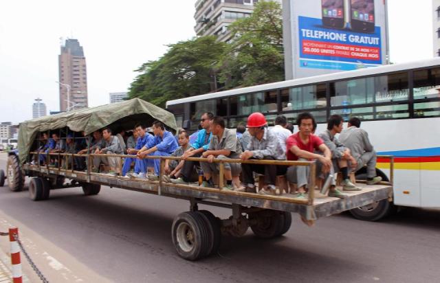 In this photo taken on May 20, 2015, Chinese workers travel on the back of a trailer pulled by a tractor on their way to work in Kinshasa, Democratic Republic of Congo. Congos government is bringing in outside experts including officials from the World Bank and the United Nations, to investigate the long-term impact of some $6.7 billion in contracts with Chinese companies that critics have said could exploit the central African nations mineral riches.(AP Photo/John Bompengo)