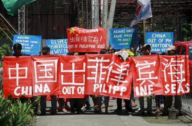Environmental activists display placards as they march towards the Chinese Embassy in Makati City, Metro Manila May 11, 2015. The activists demanded that Chinese authorities immediately put a stop to the ecological destruction caused by the reclamation activities of China in the South China Sea, which the Philippines calls West Philippine Sea. They also condemned what they say is the bullying by Chinese naval and coast guard forces of Filipino fishermen in the disputed seas, a environmental activist said. REUTERS/Romeo Ranoco